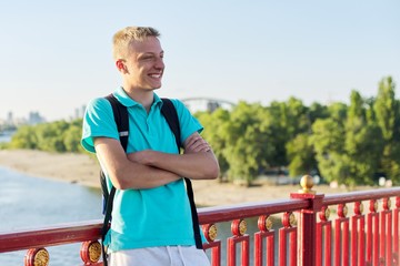 Outdoor portrait of smiling teenage boy 15, 16 years old with arms crossed