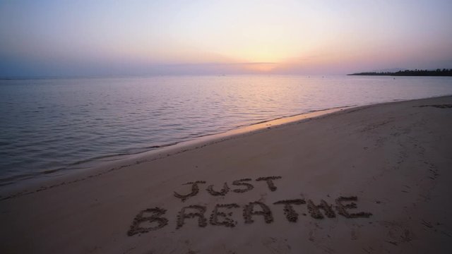Handwritten Just breathe on sandy beach at sunset,relax and summer concept,Dominican republic beach.