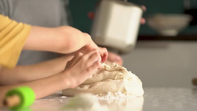 Children cooks pizza. Boy and girl having fun with father. Prepering ingredients for pizza. Children touch cooked dough.