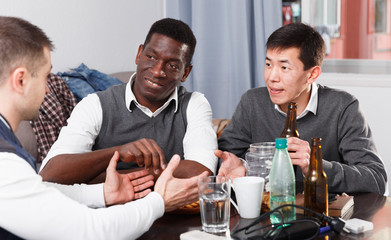 Fototapeta premium Cheerful men talking at home table