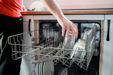 Close up of a Man Loading Dishwasher In Kitchen. Housework