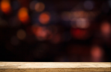 Empty wooden table top on blur light golden bokeh of cafe restaurant, bar in a dark background.