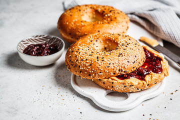 Bagels with peanut butter and berry jam on white board. Vegan food concept.