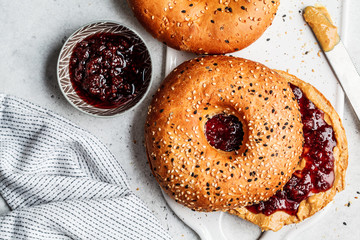Bagels with peanut butter and berry jam on white board. Vegan food concept.