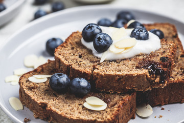 Slices of banana bread with berries and yogurt on a gray plate.
