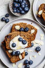 Flat lay of slices banana bread with berries and yogurt on a gray plate.