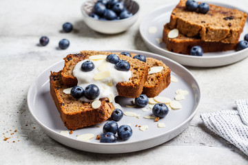 Slices of banana bread with berries and yogurt on a gray plate.
