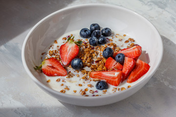 Healthy breakfast concept. Granola with milk and berries in white bowl.