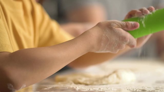 Children cooks pizza. Boy and girl having fun with father. Prepering ingredients for pizza. Roll out the dough with a rolling pin