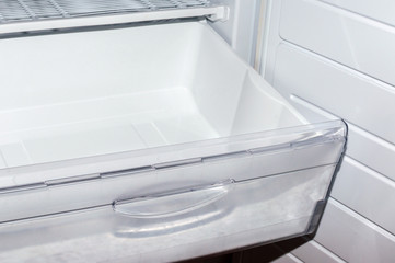 Open plastic white container drawer in refrigerator. Selective focus.