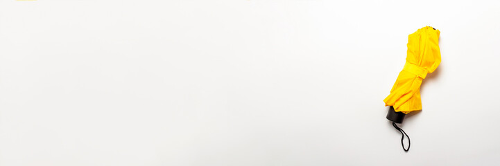 Folded yellow umbrella on an isolated white background. Concept weather forecast, rain. Banner. Flat lay, top view