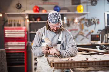 Male carpenter working on old wood in a retro vintage workshop.