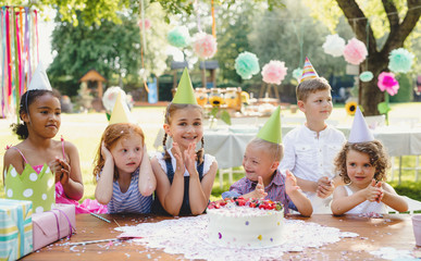 Down syndrome child with friends on birthday party outdoors in garden.