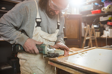 Male carpenter working on old wood in a retro vintage workshop.
