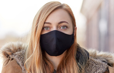 health, safety and pandemic concept - young woman wearing black face protective reusable barrier...