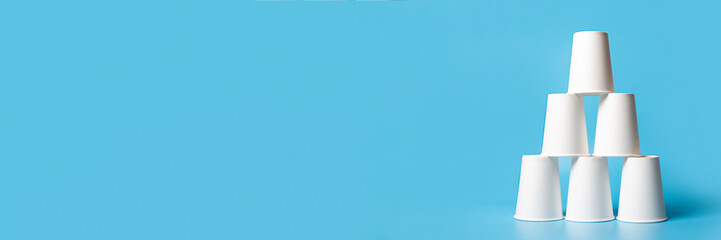 Pyramid-shaped paper cups on a blue background. Concept of corporation, friendly team, career...