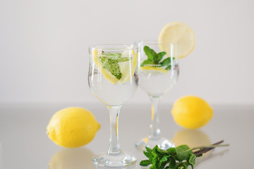 Lemon and mint lemonade. Detox drink with fresh peppermint, lemon fruit and sparkling mineral water on glass table