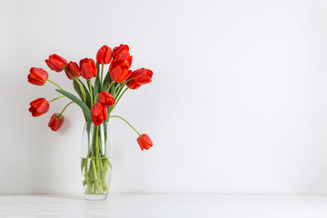 Red tulips in a vase on the table, on a white background. Postcard blank.