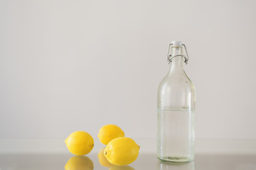 Lemons and bottle of sparkling mineral water on glass table. Minimal style
