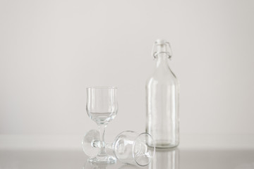 Empty glasses and empty bottle for water or lemonade on transparent table. Glassware for cafe, restaurant, bar or home gathering