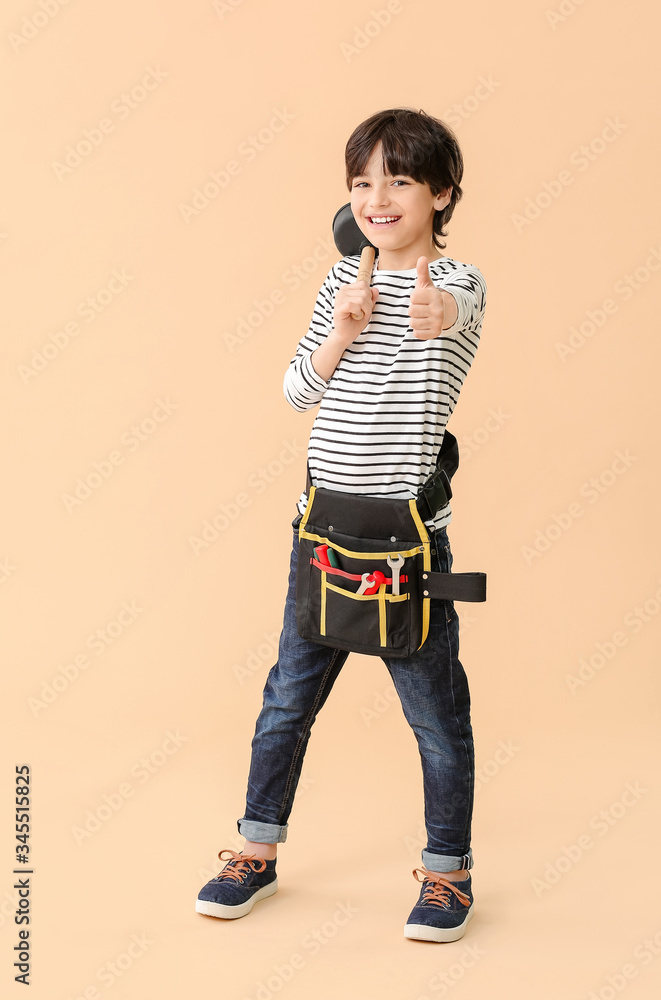 Poster portrait of little plumber showing thumb-up gesture on color background