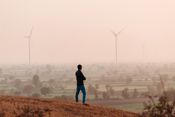 Indian man standing on top of hill in front of the windmills during the sunset at Wankaner, Gujarat, India