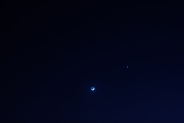 Young Moon and Venus on a dark night sky.