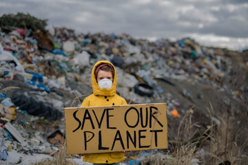 Small child holding placard poster on landfill, environmental pollution concept.