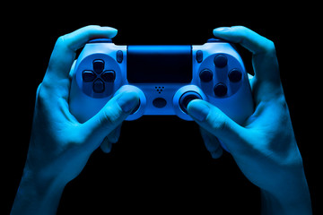 Hyman hands holding white video game gamepad in neon lights isolated on a black