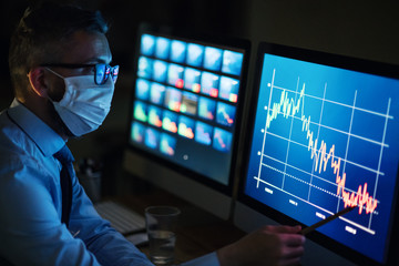 Businessman with computer sitting at desk, working late in office. Financial crisis concept.