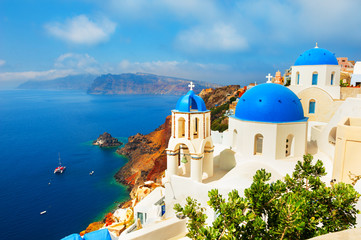 Fototapeta premium Tradycyjny biały kościół grecki z niebieskimi kopułami w Oia, wyspa Santorini, Grecja. Słynny cel podróży