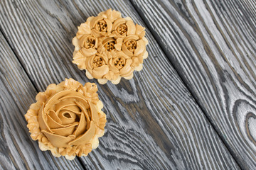 Half a cake decorated with butter cream flowers. The cream has a caramel color. On brushed pine boards painted black.
