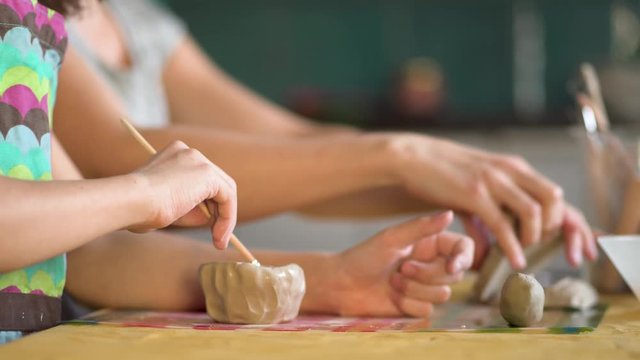 The manufacture of ceramics. Girl sculpts from clay with mother.