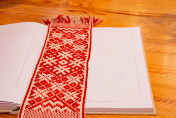 Latvian traditional folk belt called Lielvard belt on a table on a diary. Latvian sighs and symbols