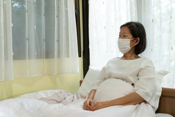portrait picture of senior asian woman wearing face mask to avoid covid-19 or coronavirus infection during quarantine at home. social distancing and new normal lifestyle concept