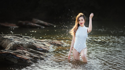Woman in white swimming suit standing in the river. Female in white swimming suit relaxing in the river on a summer day.