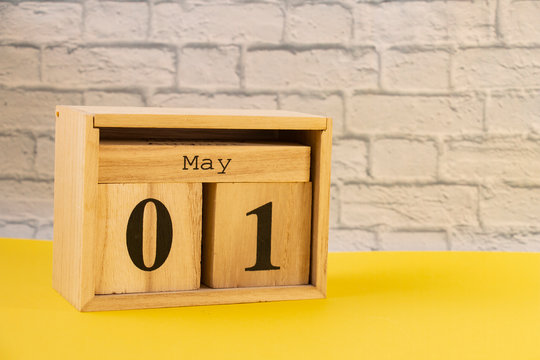 The 1 of May. Image of may 1 wooden calendar on a yellow table. Empty space for text. International Workers Day