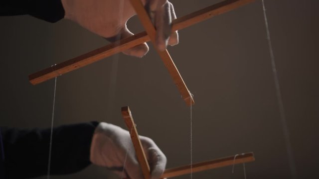 An anonymous puppeteer manipulates people's minds and behavior. Puppet master and marionettes's hands in gloves