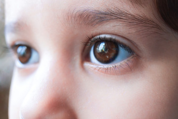 Close-up of serious kids brown eyes. Portrait of caucasian child girl. Girl don't looks at camera