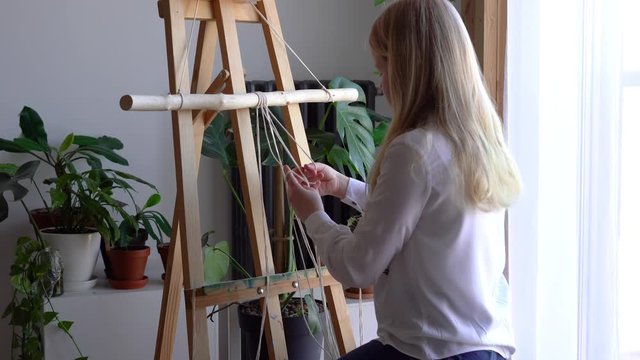 stay at home. work during the quarantine - a girl in the living room mural weaving of the ropes in the macrame technique