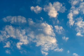 White clouds against a blue spring sky at sunset day