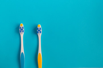 two beautiful toothbrushes blue and yellow on a blue background.view from above