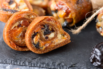 rolls with dried fruits, nuts and honey on black stone, Oriental sweets, healthy snack
