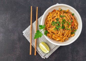 Asian chili noodles with vegetables, soy sauce, and coconut milk. Vegetarian dinner with bamboo chopsticks. Top view, copy space