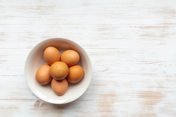 Free-range organic brown eggs in bowl on wooden background