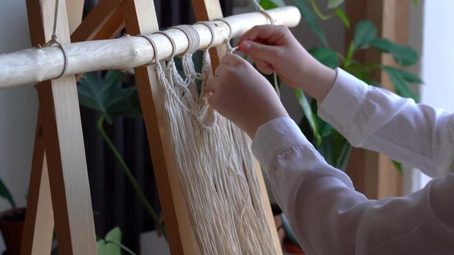 stay at home. work during the quarantine - a girl in the living room mural weaving of the ropes in the macrame technique