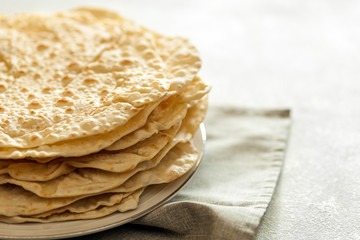 Stack of fresh homemade flat bread (pita) on plate. Copy space for text.