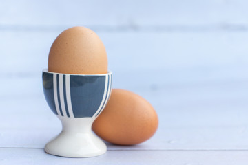 Egg served on porcelain egg holder on the wooden table with copy space.