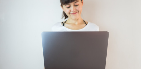 Young woman holding laptop computer and smiling.