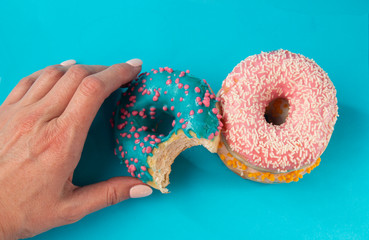 girlâ€™s hand holds a blue donut, on a blue background, sweet dessert festive